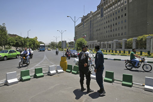 Police officers stand guard as vehicles drive past Iran's parliament building in Tehran