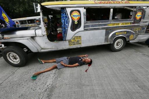 A bloodied protester lies next to a passenger vehicle after he was injured in a violent dispersal outside the U.S. Embassy in Manila