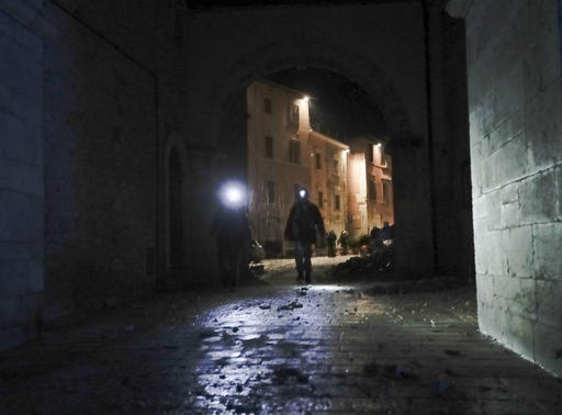 Rescuers and residents wander around the small town of Visso in central Italy under eavy rain