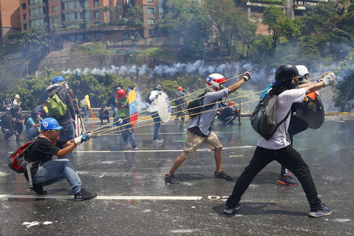 Anti-government protesters aim a slingshot during clashes with security forces blocking and opposition march attempting to reach the Supreme Court in Caracas