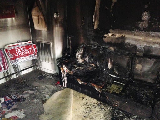 A burned couch is shown next to warped campaign signs at the Orange County Republican Headquarters in Hillsborough