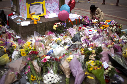 A woman places flowers at a memorial for the victims of a suicide attack at a concert by Ariana Grande that killed more than 20 people Monday night in central Manchester