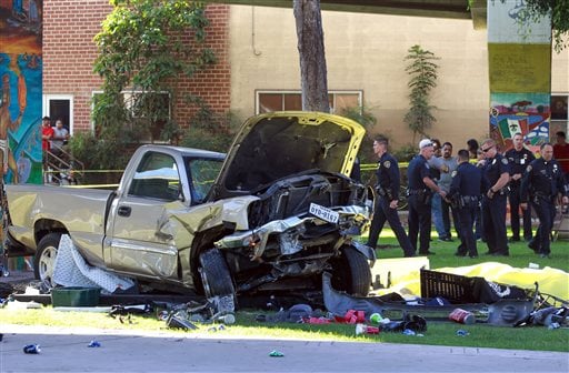 Police stand near the pickup truck that landed at Chicano Park after it flew off a ramp to the San Diego Coronado Bridge in San Diego on Saturday
