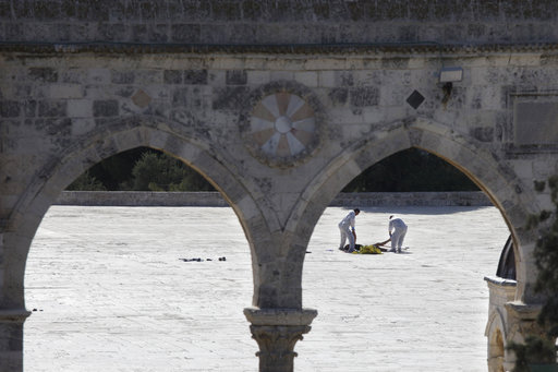 Israeli police forensic experts inspect the body of a Palestinian at the scene of an attack in the Al Aqsa Mosque compound in Jerusalem's Old City