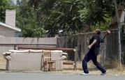 A man tosses a football in the street in San Bernardino