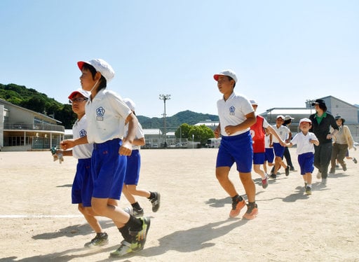 Schoolchildren leave the compound of their school during an evacuation drill in Abu town