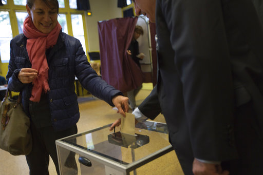 A woman casts her vote for the first-round presidential election at a polling station in Paris
