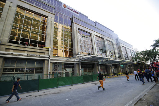 Rescuers run past as smoke comes out from the windows of a hotel at the Resorts World Manila complex