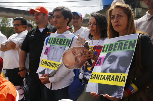 Relatives of jailed opposition leaders hold posters asking for the liberation of their loved ones outside the Ramo Verde military prison in Los Teques