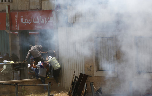 Palestinians run for cover from tear gas shot by Israeli soldiers during clashes in the West Bank city of Bethlehem