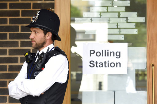 A police officer is stationed outside a polling station at Cubitt Town Infant and Junior School on the Isle of Dogs in London