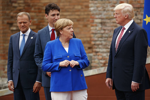 German Chancellor Angela Merkel talks with President Donald Trump during a family photo with G7 leaders at the Ancient Greek Theater of Taormina