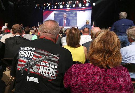 NRA attendees Bill and Karen Geittman  watch a video of President Donald Trump while waiting for him to arrive for a keynote at the NRA-ILA Leadership Forum on Friday