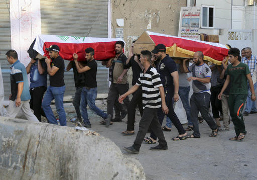 Mourners carry the Iraqi flag-draped coffins of bomb victims during their funeral procession in Baghdad