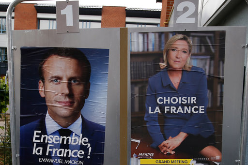 Election campaign posters for French centrist presidential candidate Emmanuel Macron and far-right candidate Marine Le Pen are displayed in front of the polling station where Marine Le Pen will vote in Henin Beaumont