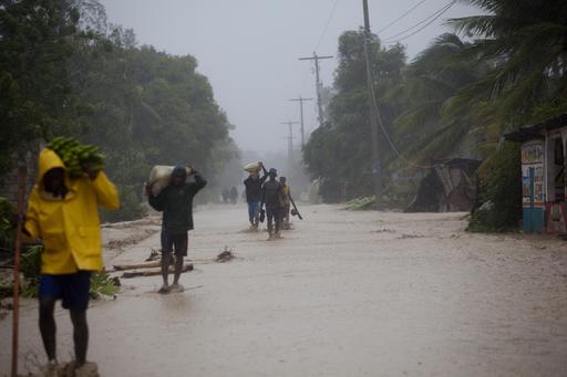 Residents walk in flooded streets as they return to their homes in Leogane