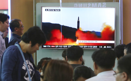 People watch a TV news program showing a file image of a missile launch by North Korea