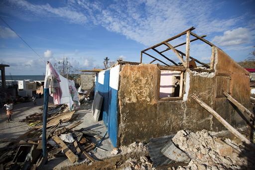 A girl walks in front of a house that was destroyed by Hurricane Matthew in Dame-Marie