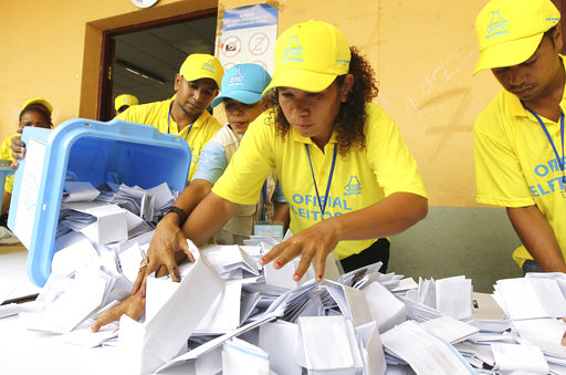 Electoral workers empty a ballot box as votes are counted during the parliamentary election in Dili
