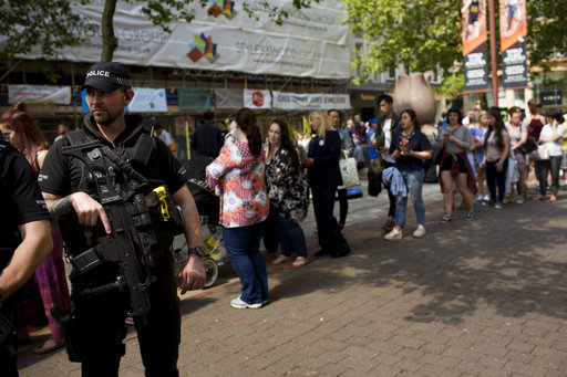 A police officer patrol as people queue to place flowers at St Ann's square in central Manchester