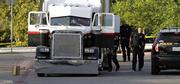 San Antonio police officers investigate the scene where eight people were found dead in a tractor-trailer loaded with at least 30 others outside a Walmart store in stifling summer heat in what police are calling a horrific human trafficking case