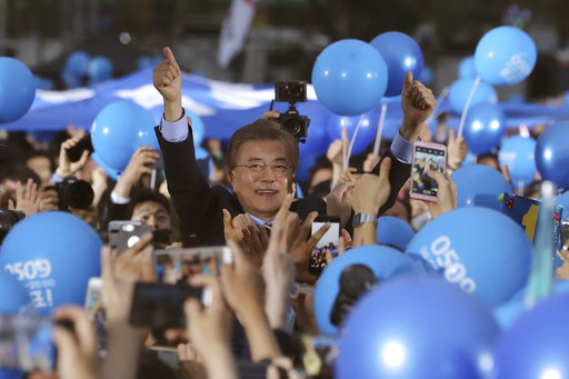 South Korean presidential candidate Moon Jae-in of the Democratic Party gives his supporters a thumbs-up sign upon his arrival at an election campaign in Seoul