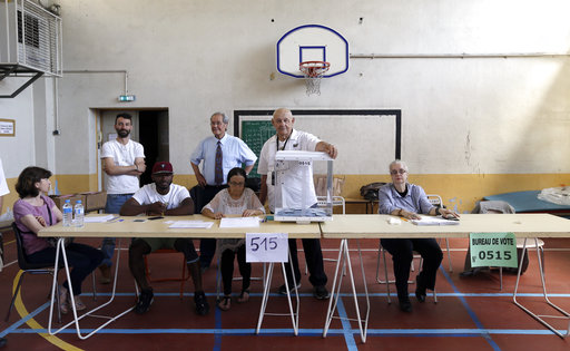 Volunteers wait for people at a polling station during the first round of parliamentary elections in Marseille