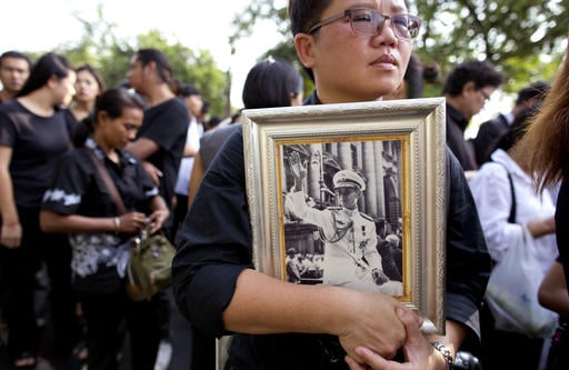 A Thai woman holds on to a portrait of Thai King Bhumibol Adulyadej in a line to offer condolences for the king at Grand Palace in Bangkok