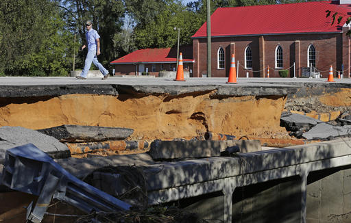 A man walks across a road damaged by floodwaters caused by rain from Hurricane Matthew in Fayetteville