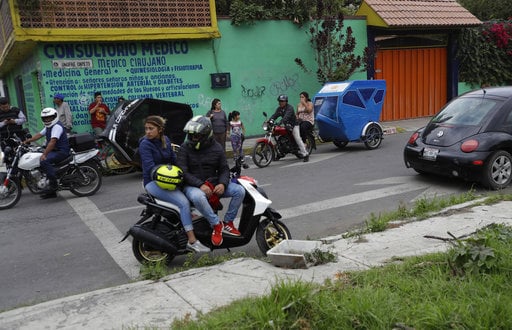 Residents and motorcycle taxi drivers stop to look at marines blocking the area where a suspected drug gang leader and seven others were killed in a shootout in the Tlahuac district of Mexico City