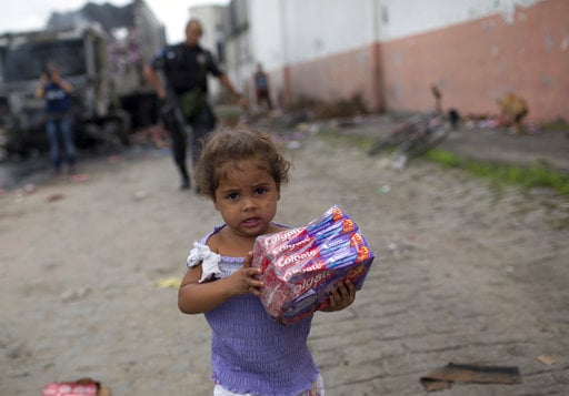 A child walks off with a pack of toothpaste she took from a cargo truck allegedly set on fire by drug traffickers