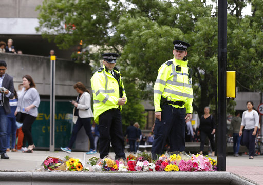 Police officers walk by floral tributes in the London Bridge area of London