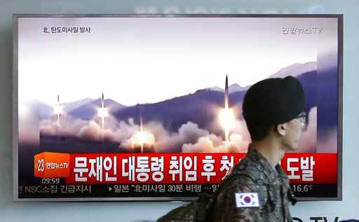 A South Korean army soldier walks by a TV news program showing a file image of missiles being test-launched by North Korea