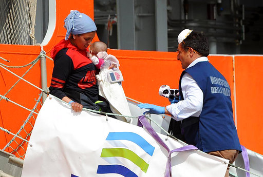 A woman carrying a baby disembarks from the Norwegian ship Siem Pilot