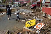 A woman with her two children walk past debris left by Hurricane Irma in Charlotte Amalie