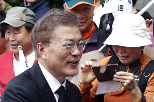 Newly elected South Korean President Moon Jae-in greets his neighbors and supporters as he leaves his house in Seoul