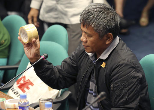 Former Filipino militiaman Edgar Matobato shows the kind of tape they use to wrap up dead bodies as he testifies before the Philippine Senate in Pasay
