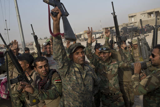 Iraqi army soldiers raise their weapons in celebration on the outskirts of Qayyarah