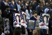 People hold up signs with the names and pictures of victims of the 9/11 terrorist attacks during a ceremony at ground zero in New York