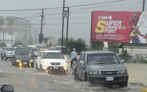 Cars drive along a street under heavy rain in downtown Kingston Jamaica
