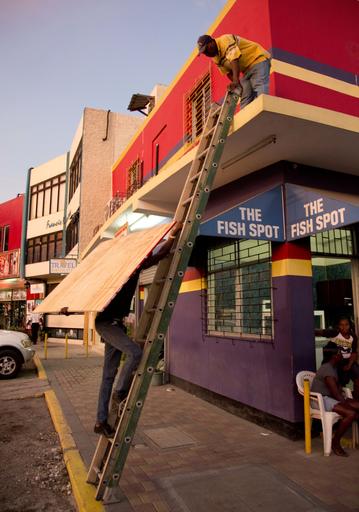 A worker hauls a board to use on a storefront window as protection against hurricane Matthew in Kingston