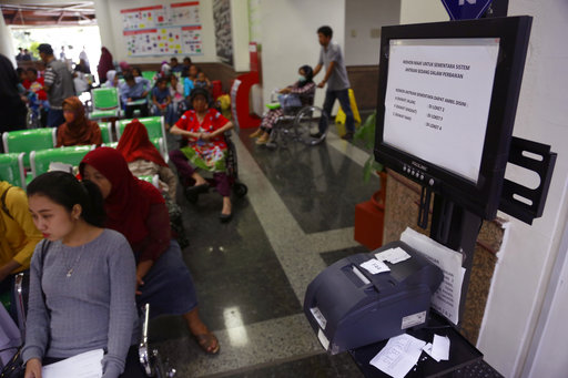Patients wait near a queue number dispenser affected by "WannaCry" attack at Dharmais Cancer Hospital in Jakarta