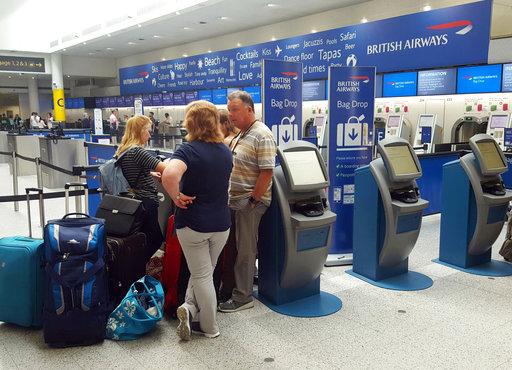 Passengers stand at the British Airways check-in desk after the airport suffered an IT systems failure