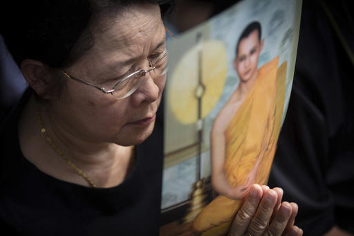 A Thai woman holds a picture of the late King Bhumibol Adulyadej while waiting to pay respect to him outside the Grand Palace in Bangkok
