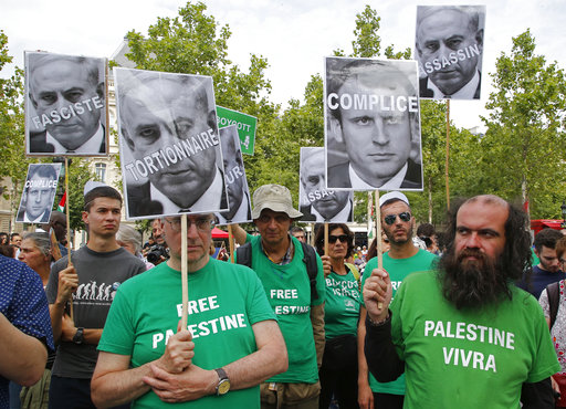 Pro-Palestinian activists hold pictures of Israeli Prime Minister Benjamin Netanyahu and French President Emmanuel Macron as they gather to protest Israeli Prime Minister's visit to France in Paris