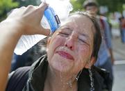 A counter demonstrator gets a splash of water after being hit by pepper spray at the entrance to Lee Park in Charlottesville