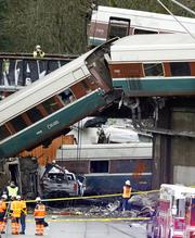 Cars from an Amtrak train that derailed above lay spilled onto Interstate 5 alongside smashed vehicles Monday