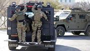 Law enforcement personnel load into a vehicle during a search of the hills near the mouth of Red Butte Canyon