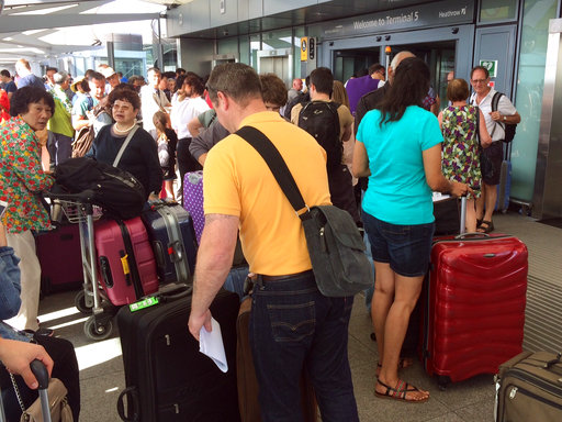 Passengers stand with their luggage outside Terminal 5 at London's Heathrow airport after flights were canceled due to the airport suffering an IT systems failure