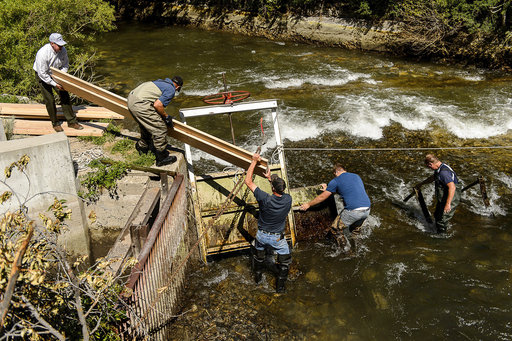 Workers put in a dam to divert and lower water levels in the Provo River
